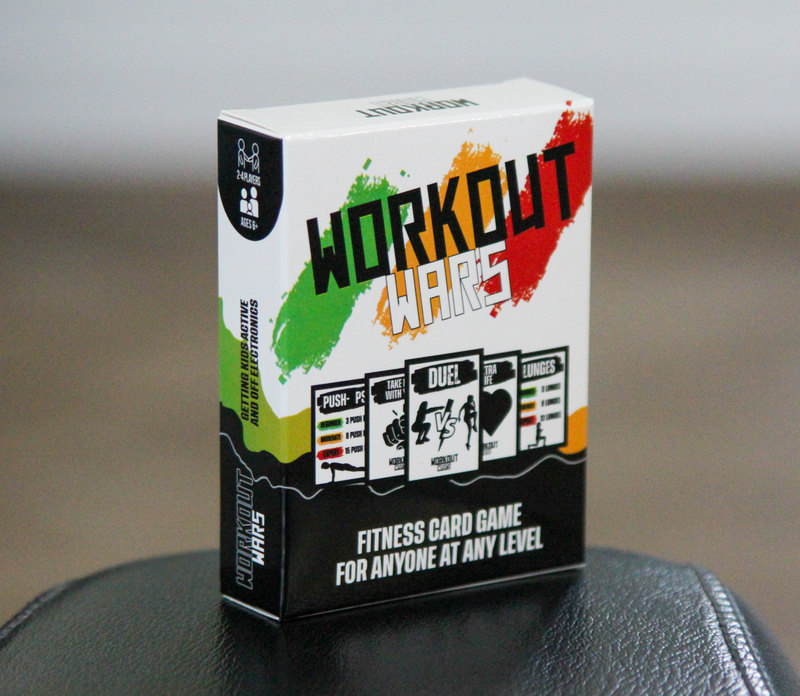 The real Workout Wars box on a dark bench, with green, orange and red brushstrokes on its white packaging.